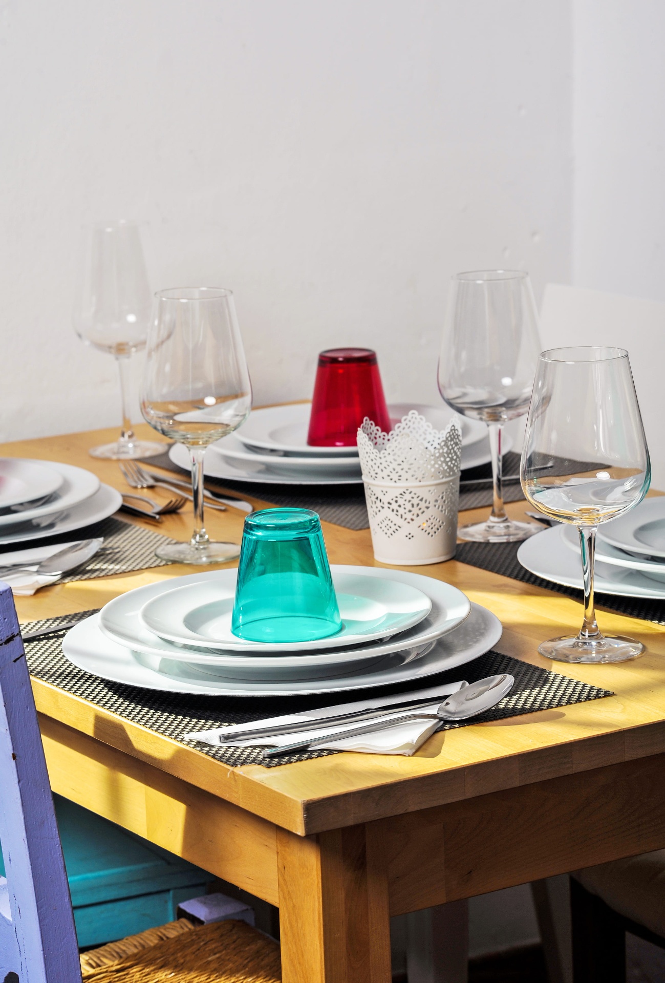 Mesa posta no restaurante com loiça branca e copos coloridos