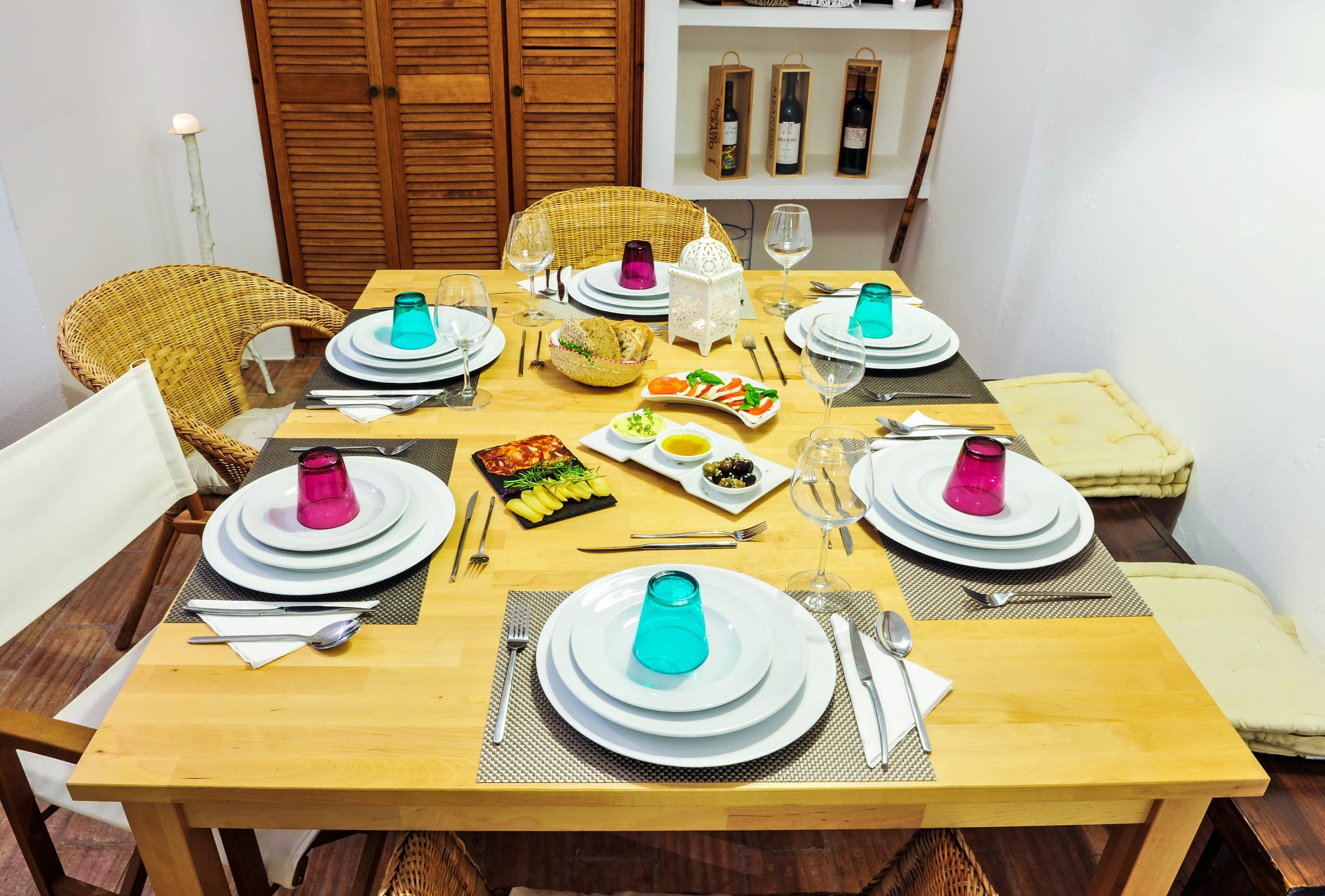 Mesa posta na Casa Amarela com copos de cor, pratos de cerâmica e detalhes artesanais