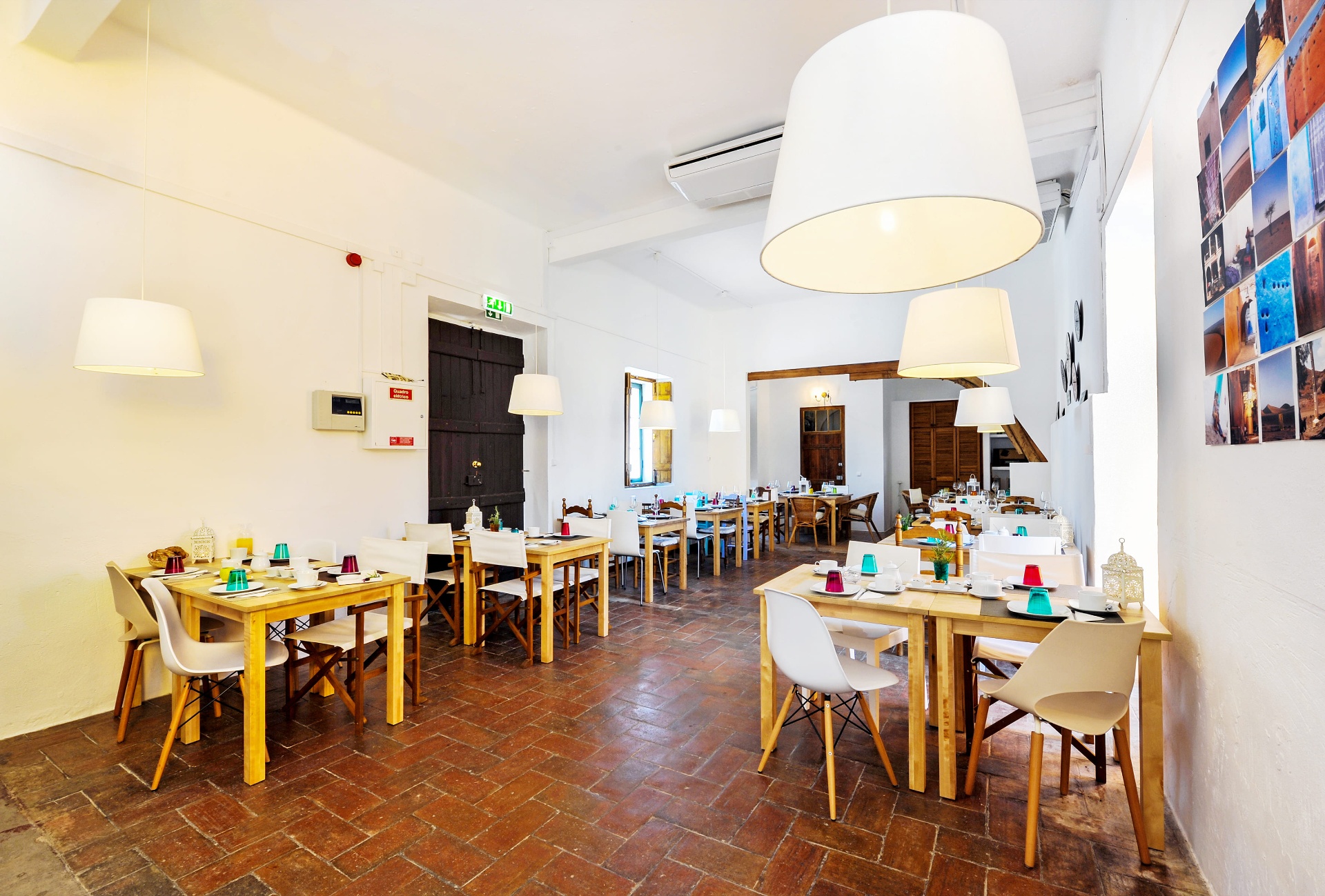 Sala ampla do restaurante com chão de tijoleira e candeeiros suspensos